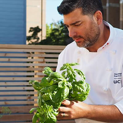 Chef David Speight outdoors, holding a bunch of basil.