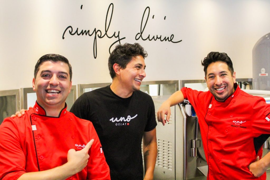 Three Uno Gelato team members smiling at each other and the camera in their work space.