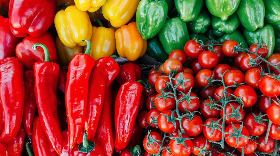 Assortment of vegetables: sweet peppers, yellow and green peppers, and vine tomatoes.