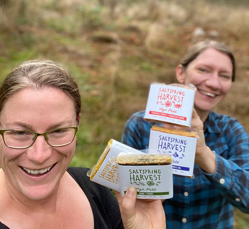 Salt Spring Harvest owners smiling at the camera while holding four of their packaged patés.