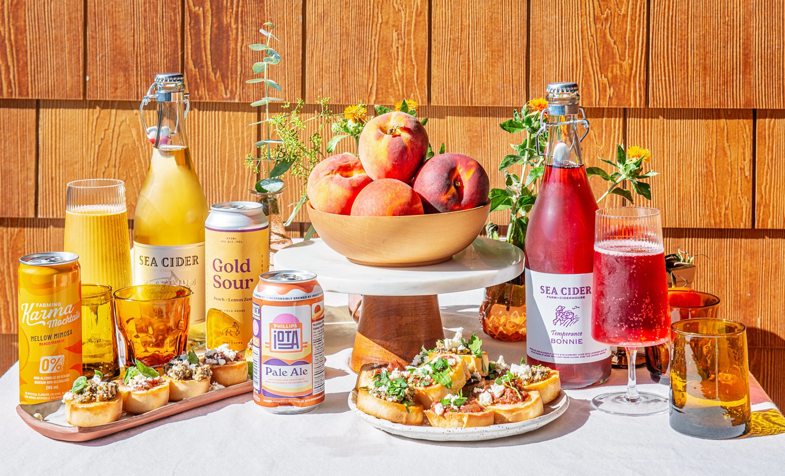 A late summer spread featuring appetizers and Buy BC products including Farming Karma Mocktails, Sea Cider, Field House Brewing beer, and Phillips Brewing non-alc beer. 