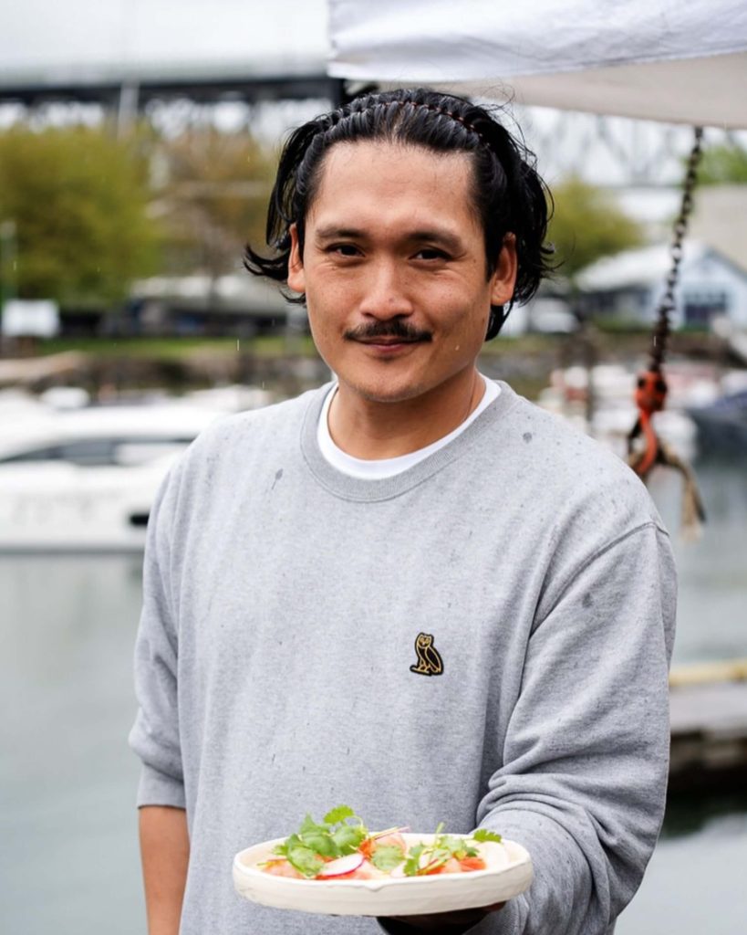 Chef Mark Singson presenting a plate on the dock of a Vancouver marina.