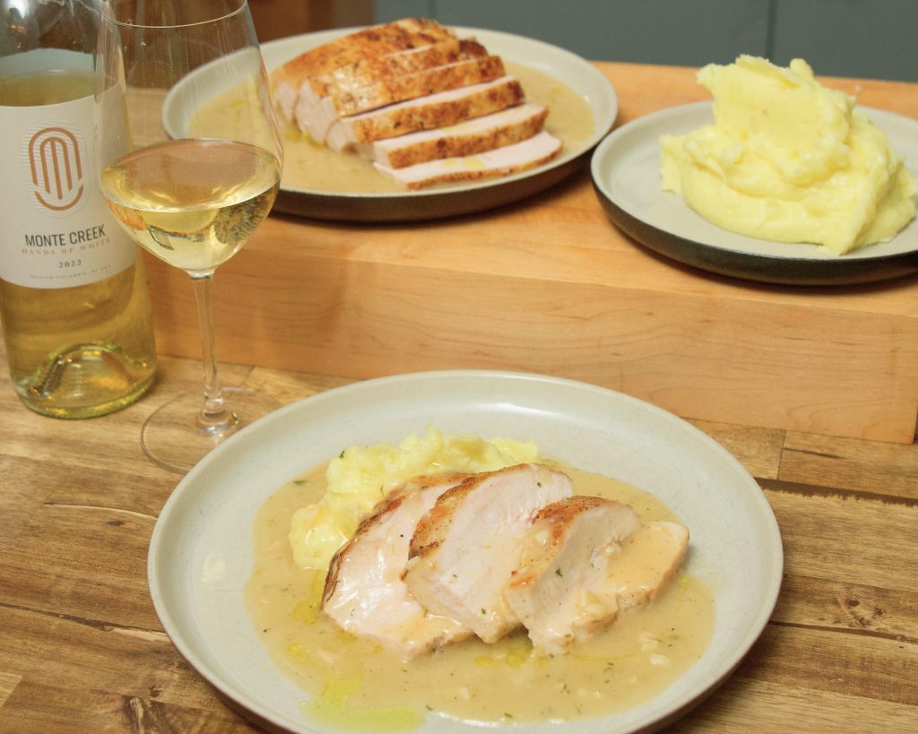 Turkey dinner plated on a ceramic dish with sliced roasted B.C. turkey breast, and mashed potatoes and gravy, with a bottle and glass of Monte Hands Up White wine. And a whole roasted turkey breast sliced and plated with gravy beside a separate plate of mashed potatoes.