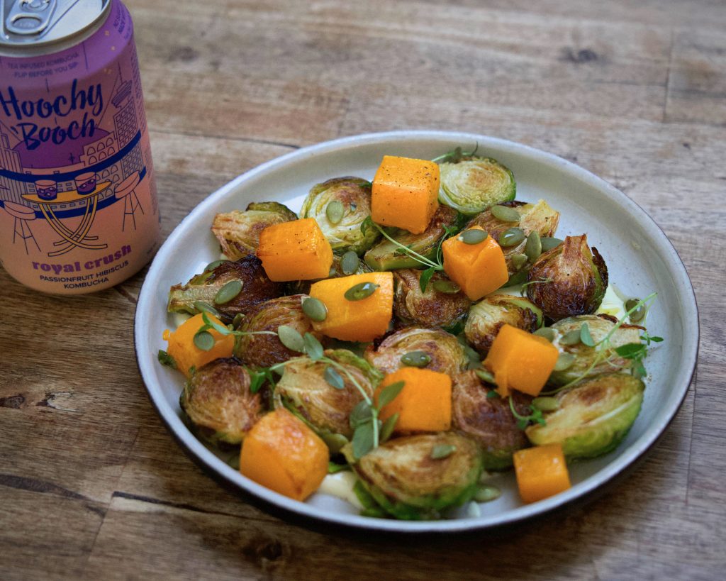 Plate of roasted B.C. Brussels sprouts and winter squash with a can of Hoochy Booch Kombucha beside it. 