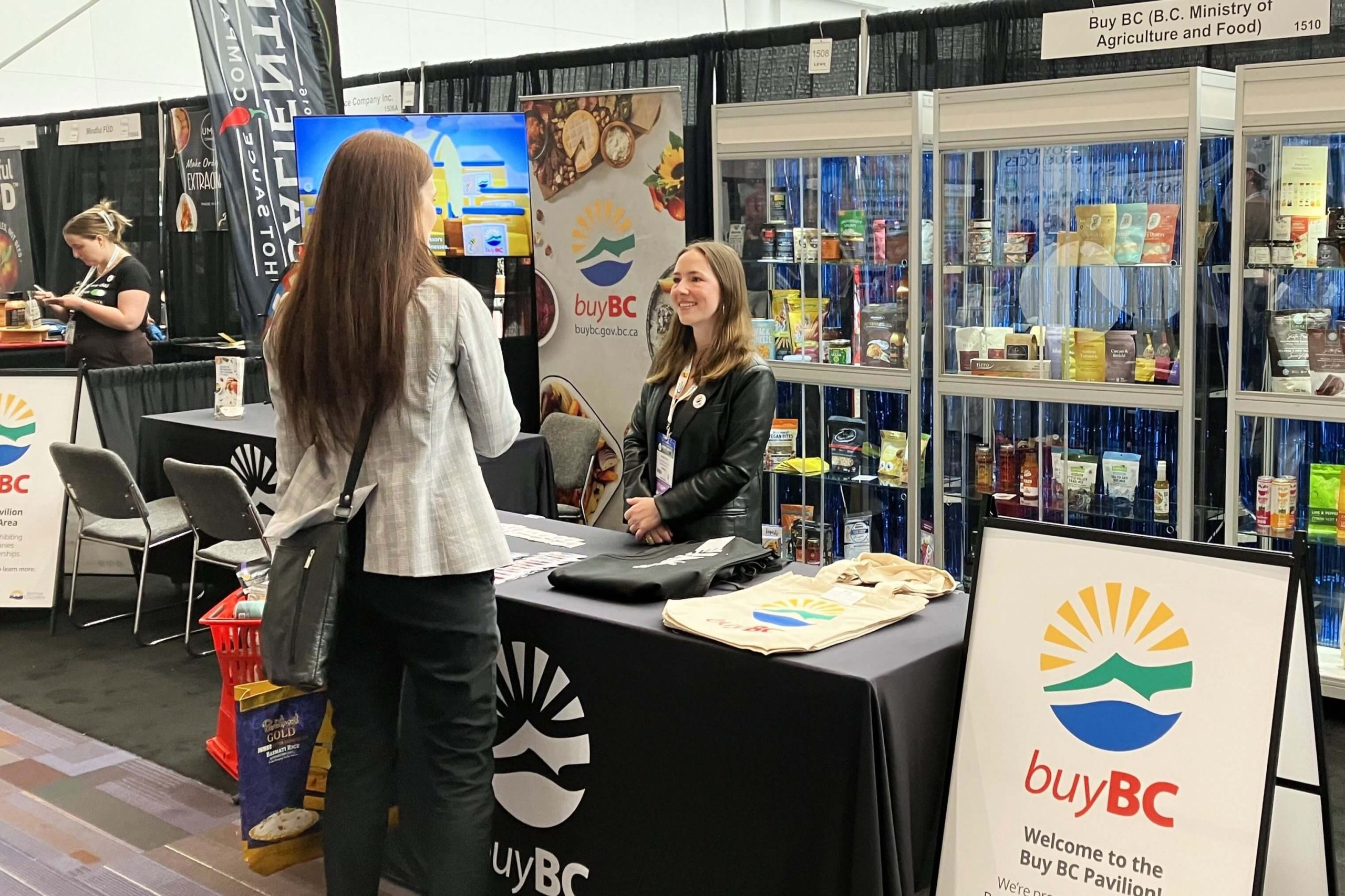 Buy BC team member talking with an attendee in the Buy BC Pavilion at Grocery & Specialty Food (GSF) West 2024.