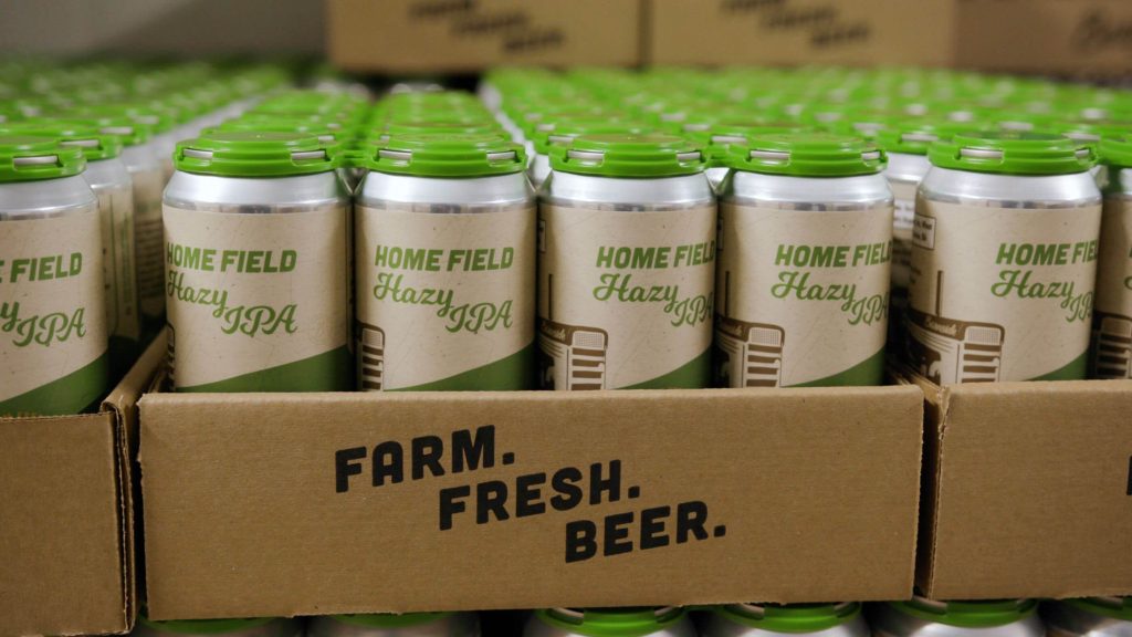 Green and white tall cans of B.C. beer packaged in cardboard flats.