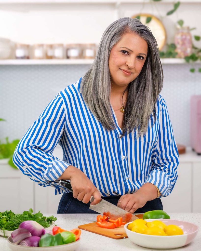 A woman in a kitchen chopping vegetables.